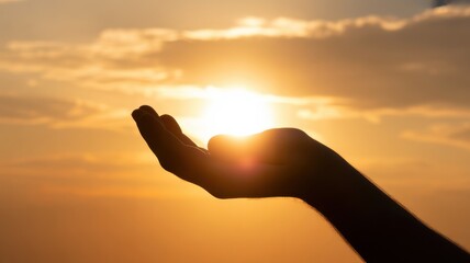 Human hand silhouette cradling bright sun against orange sky with clouds sunset