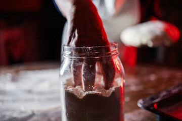 Hand reaching into flour jar for baking