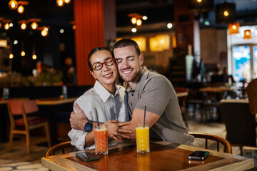 Happy couple hugging while enjoying drinks at restaurant