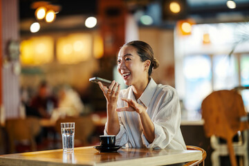 Woman sending voice message on smartphone in cafe