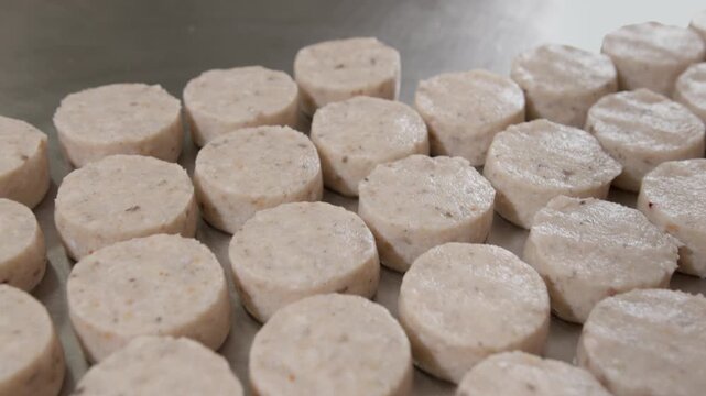 Cook lifts metal forming ring releasing soft rounded patty onto cold polished surface. Smooth careful gesture shapes tidy line of fragrant mixed minced mass ready for freezing