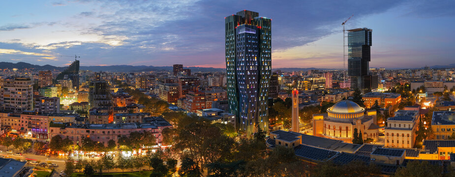 Fototapeta Aerial  dusk panorama of central Tirana showcasing modern towers, illuminated streets, and the city skyline. 