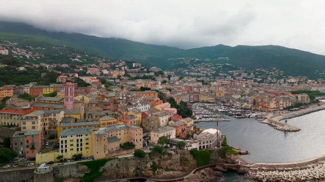 Cinematic Aerial Drone Shot Over Bastia's Historic Genoese Citadel and Colorful Old Port Harbor on the Mediterranean Coast of Corsica, France, on a Cloudy Spring Day.