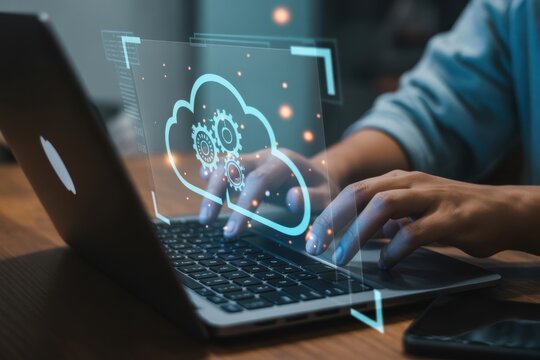 Cloud Computing and Technological Advances: A person engrossed in work, using a laptop with a digital cloud computing graphic overlaid. - Powered by Adobe