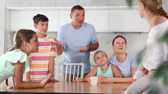 Concept of big friendly family - children of different ages and parents communicate in the home kitchen