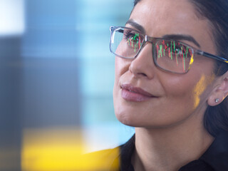 Financial analyst viewing market data with reflections of stock graphs