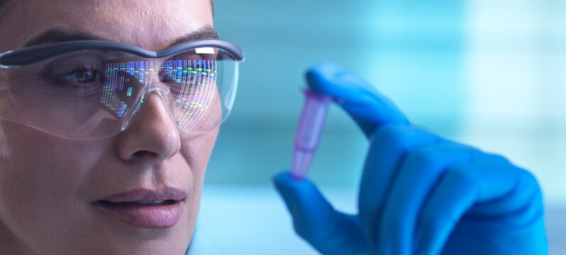 Scientist analysing DNA sample in laboratory with protective eyewear