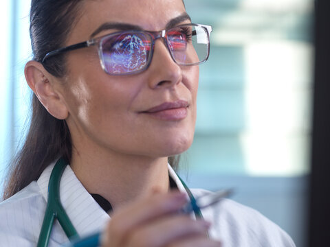 Medical professional analyzing brain scan with reflection in eyeglasses