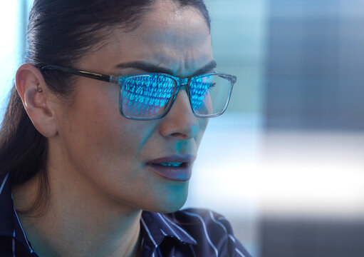 Woman looking at computer screen during cyber attack with binary code reflection