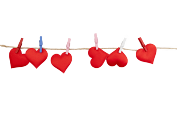 Red fabric hearts hang on a line with clips. This setup is perfect for creating a decoration for Valentine's Day celebrations at home or in a classroom.