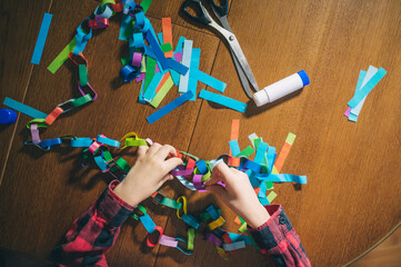 Child making a colorful paper chain for Christmas and New Year decoration