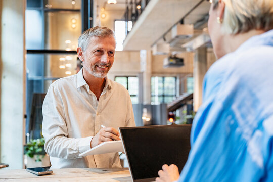 Smiling colleague in meeting with laptop in modern office environment