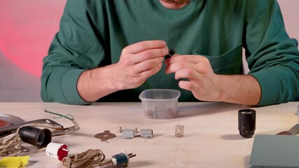 Restoration master carefully checking components of disassembled vintage lamp and putting switches, springs, terminals and sockets into box, examinees quality of supplies. Creative upcycling hobby.