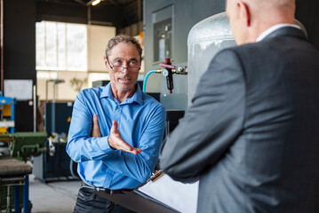 Manager and engineer having business discussion in production hall