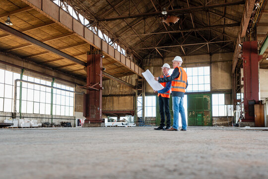 Engineers discussing project plans in industrial production hall