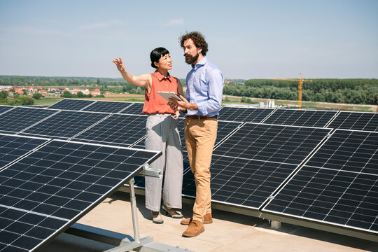 Business meeting by solar panels discussing renewable energy outdoors