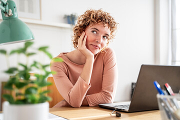 Cheerful woman smiling and thinking at a bright home office workspace