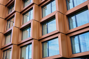 Modern building facade with geometric metal panels and large reflective windows. Concept of contemporary architecture, urban exterior and commercial property design.