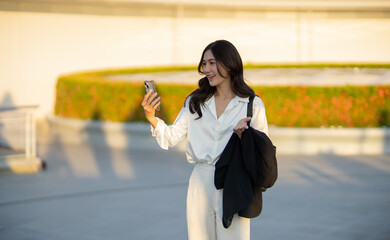Confident Asian businesswoman smiling in a modern corporate setting, attractive professional lady standing outdoors, showcasing success, beauty, career ambition, and cheerful lifestyle.