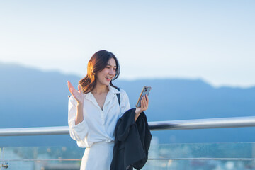 Confident Asian businesswoman smiling in a modern corporate setting, attractive professional lady standing outdoors, showcasing success, beauty, career ambition, and cheerful lifestyle.
