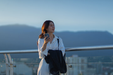 Confident Asian businesswoman smiling in a modern corporate setting, attractive professional lady standing outdoors, showcasing success, beauty, career ambition, and cheerful lifestyle.