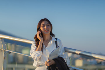 Confident Asian businesswoman smiling in a modern corporate setting, attractive professional lady standing outdoors, showcasing success, beauty, career ambition, and cheerful lifestyle.