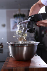 The process of making mashed potatoes in a stainless steel potato grinder, close-up. The cook's hands. Cooking vegetable and vegetarian dishes.