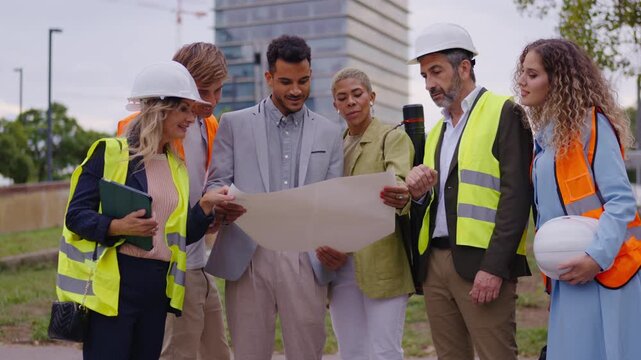 Diverse team of architects and engineers discussing construction blueprint