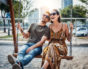 Zakochana para lub para bliskich przyjaciół siedzi na huśtawce rozmawiając i śmiejąc się