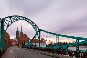 Obraz premium Green Steel Bridge With Love Locks And Cathedral Towers, City River Architecture Landmark Oldtown Travel Walkway. Copy Space