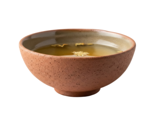 Isolated earthen bowl of herbal tea showing dried herbs floating on surface, a natural remedy
