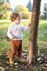 Portrait of happy little boy playing by himself in the park. Colorful fall outdoors