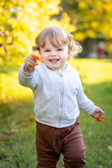 Portrait of happy little boy playing by himself in the park. Colorful fall outdoors