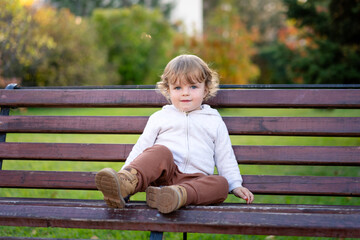Portrait of happy little boy playing by himself in the park. Colorful fall outdoors