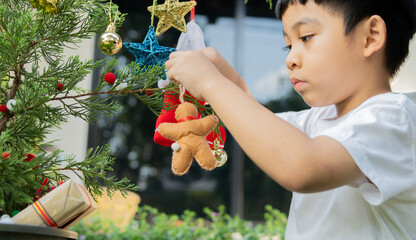 Holiday concept. Side view of Asian little boy prepare to decorate the Christmas tree