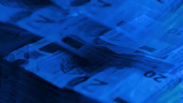 Money piles bathed in blue hue suggest detachment from emotional value