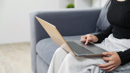 部屋でノートパソコンを使う女性