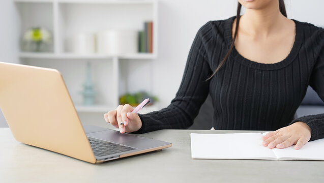 A woman studying while looking at a laptop in her room