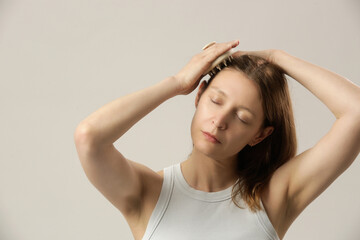 Fototapeta premium Girl doing herself a head massage using a scalp massager, stimulating hair growth, microcirculation, help to distribute natural oils more evenly across the scalp 