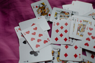 A deck of playing cards is scattered on the pink background.
