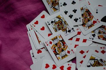 A deck of playing cards is scattered on the pink background.