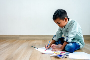 Focused Young Boy Diligently Painting And Drawing Colorful Art While Sitting Comfortably