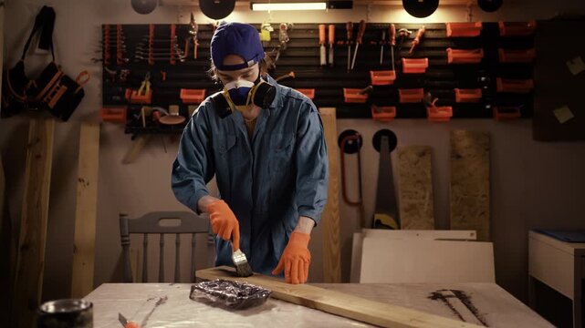 Professional Carpenter Carefully Painting Wooden Plank With Black Color In Workshop