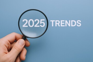 Fototapeta premium Magnifying Glass Highlighting 2025 Trends on Blue Background, Forecasting Future Insights and Analysis, Business Concept