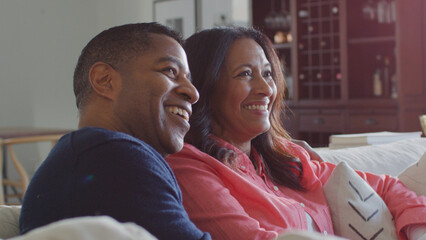 Mature Couple Sitting On Sofa At Home Watching TV Together