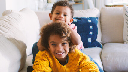 Brother And Sister Lying On Sofa At Home Watching TV Together