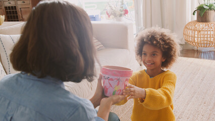 Daughter Giving Mother Plant Pot That She Has Decorated Herself Sitting On Sofa At Home