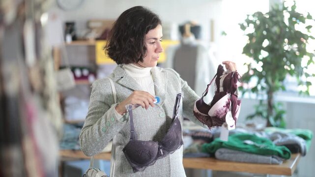  Seasonal trade sale, customer review at products in store and pick out clothes. Latin American woman search and choose bra, purchase some wardrobe items. Style and fashion type look, modern trends. 