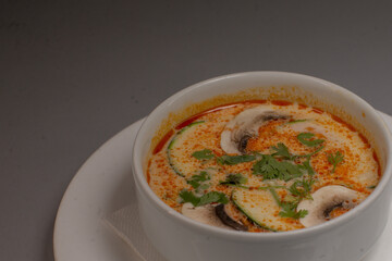 A delicious bowl of warm soup featuring mushrooms and fresh herbs, elegantly served in a pristine white bowl