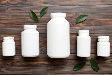 supplement pills with medicine bottle health care and medical top view. Vitamin tablets. Top view mockup bottle for pills and vitamins with green leaves, natural organic bio supplement, copy space